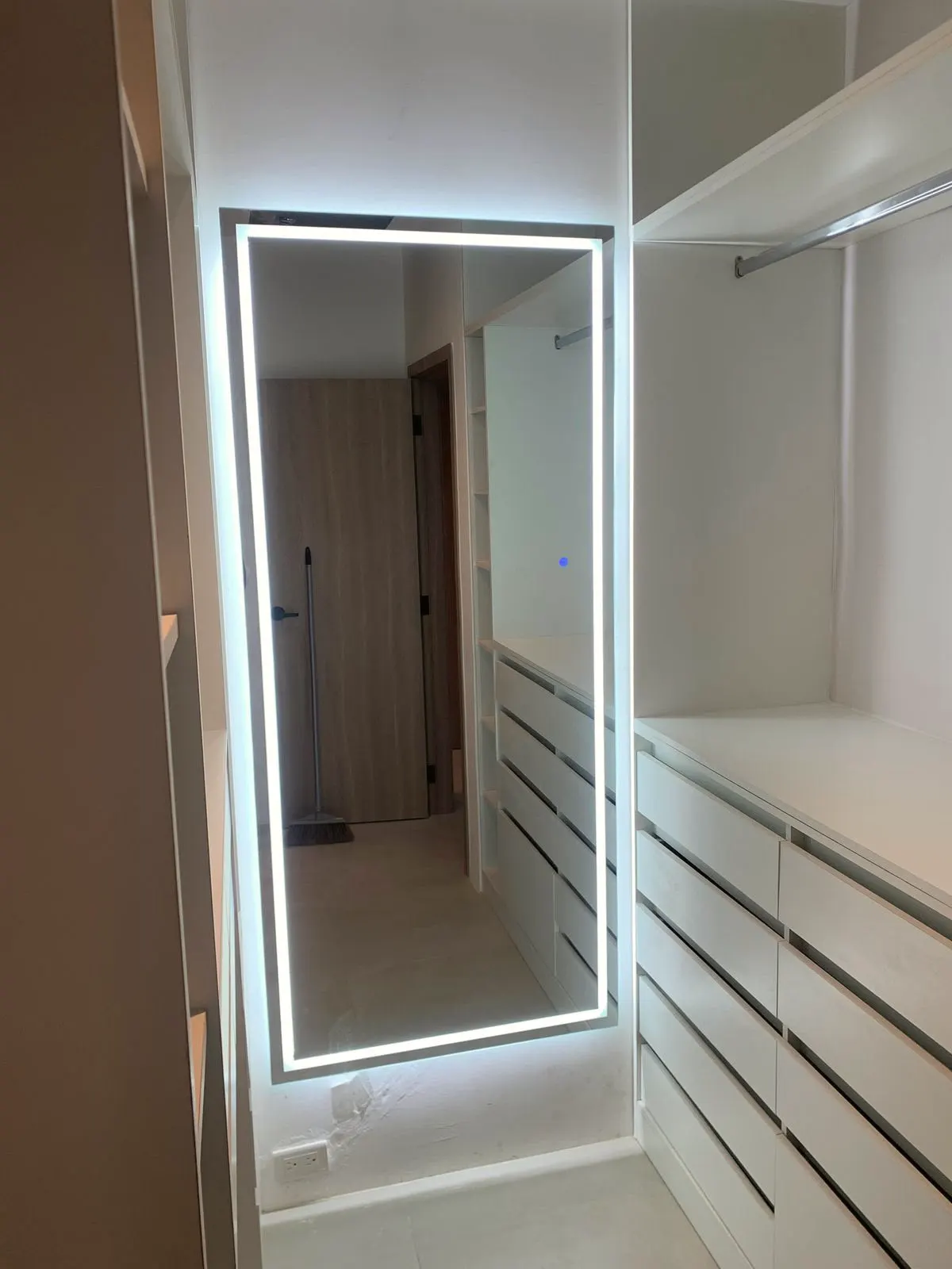 Espejo de cuerpo entero retroiluminado en un vestidor, junto a los cajones